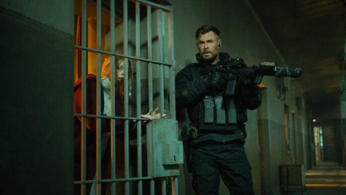 Chris Hemsworth impugna una pistola fuori da una cella di prigione in Extraction 2.