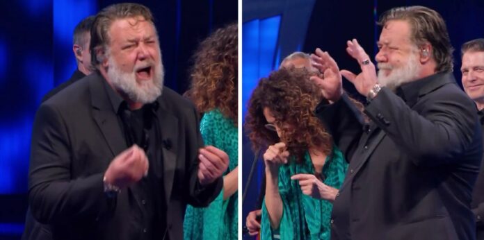 Russell Crowe sul palco di Sanremo prende in giro John Travolta, Amadeus, Mannino e gli altri non riescono a smettere di ridere