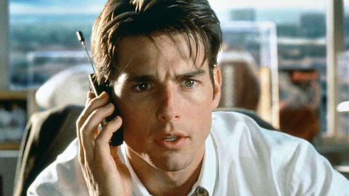 Tom Cruise è seduto alla scrivania al telefono.