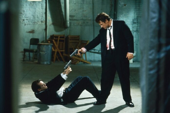 Due uomini si puntano le pistole a vicenda in Le Iene.