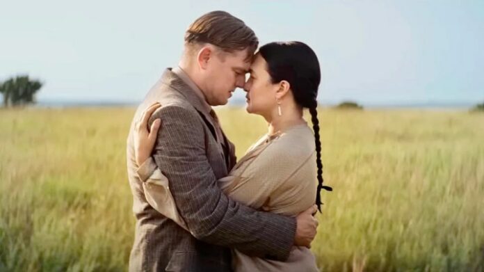 Un uomo e una donna si baciano in un campo in Killers of the Flower Moon.