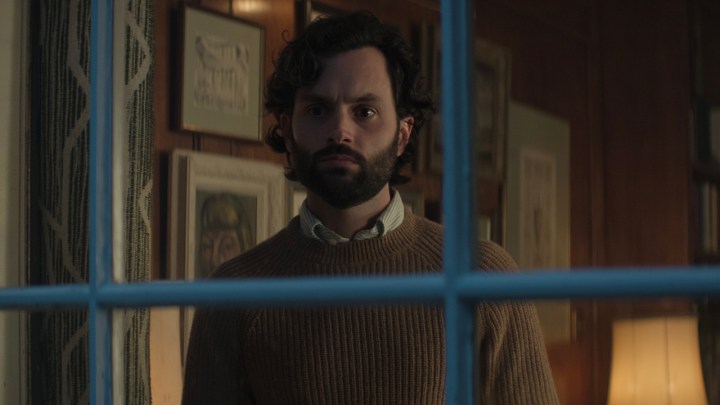 Joe Goldberg in piedi dietro una finestra con le sbarre in una scena della quarta stagione di You.
