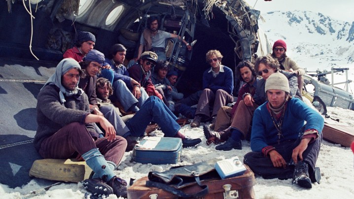 I sopravvissuti si rannicchiano tra i rottami dell'aereo in un'immagine di Society of the Snow