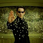 Keanu Reeves ferma una pioggia di proiettili con la mente in un'immagine di Matrix